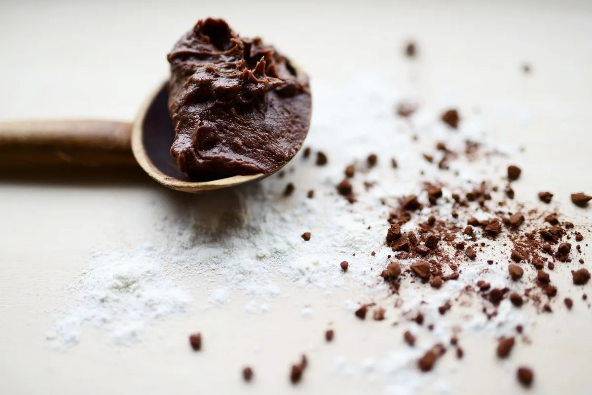 Part de gâteau chocolat‑amande sur une assiette dans une cuisine baignée de lumière naturelle