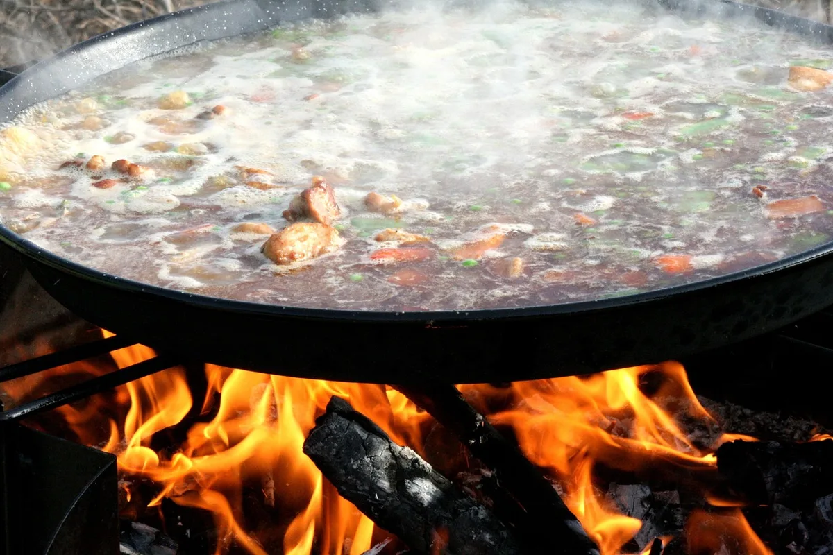 Grande poêle à paella sur une table, riz en train de cuire